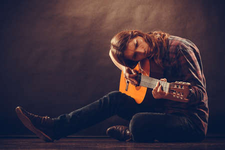 Music, hobby concept. Boy with wooden guitar. Young man is playing the instrument.の写真素材