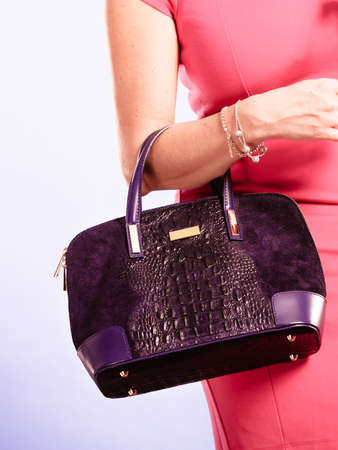 Fashion of women. Clothing and accessories. Mid aged blonde fashionable woman with handbag. Elegant lady in pink dress with black bag.の写真素材