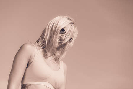 Young blonde pretty girl on beach. Woman wearing sunglasses have active time in summer with crazy hair. Summertime concept copy space.の写真素材