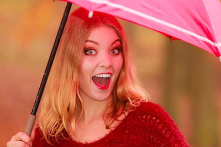 Smiling happy fashion cute woman girl in maroon sweater with umbrella relaxing in fall autumn park. Happiness and relax in forest.の写真素材