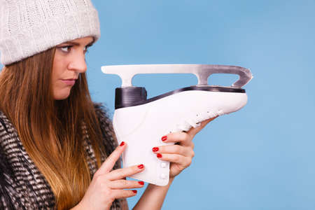 Winter, sport, people concept. Attractive lady with ice skates. Young woman wearing woolen cap.の写真素材