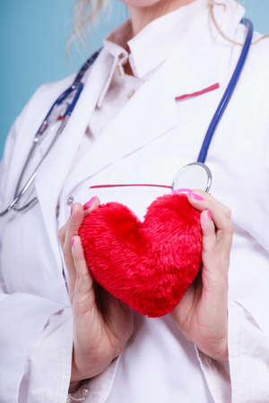 Love from working and helping people. Part body female doctor in white medical apron with heart on blue. Enjoy work concept.の写真素材