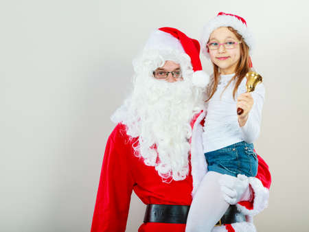 Christmas time people concept. Santa claus with little girl. Man has red outfit and child is hugging him. Shot taken at studio.の写真素材