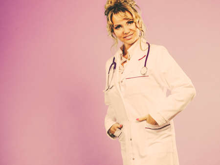 Female medical doctor in white professional uniform apron with blue stethoscope on her neck. Middle aged woman pharmacist nurse. Filtered.の写真素材