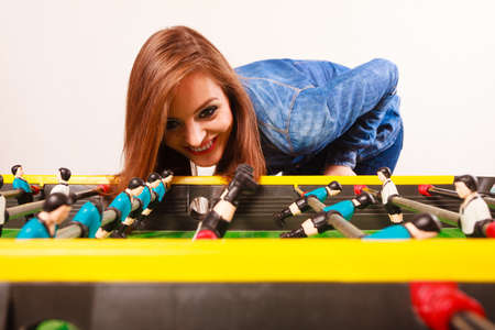 Play and fun concept. Young focused girl having fun with table soccer game. Fashionable woman playing spending free time on recreation.の写真素材