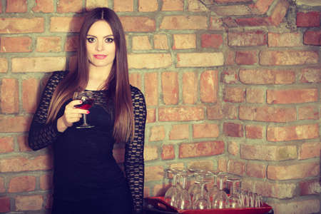 Elegant beauty lady long hair full make up wearing black dress tasting wine in rural cottage interior cellerの写真素材
