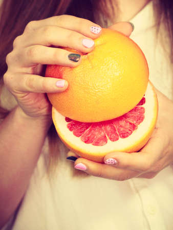 Woman attractive long hair girl colorful eyes makeup holding two halfs of grapefruit citrus fruit in hands. Healthy diet food. Summer holidays fun concept, on whiteの写真素材