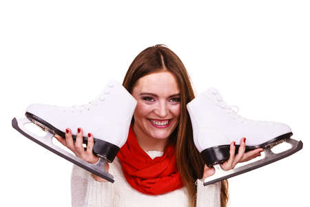 Woman with ice skates getting ready for ice skating, winter sport activity. Smiling cheerful girl wearing warm clothing on whiteの写真素材
