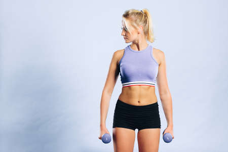 Sporty woman lifting light dumbbells weights. Fit girl exercising building muscles. Fitness and bodybuilding.の写真素材