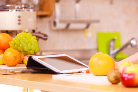 Kitchen counter with many fruits and tablet device. Healthy eating, cooking, vegetarian food, dieting and technology concept.の写真素材