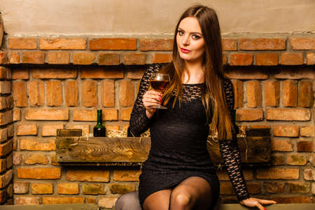 Elegant beauty lady long hair full make up wearing black dress tasting wine in rural cottage interior cellerの写真素材