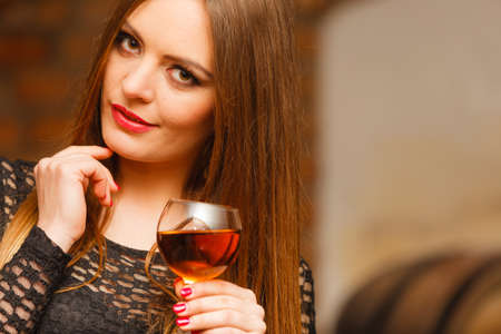 Elegant beauty lady long hair full make up wearing black dress tasting wine in rural cottage interior cellerの写真素材