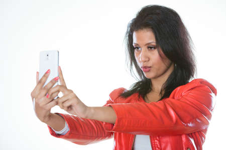 Technology and communication concept. Young attractive fashionable woman in red jacket using her...