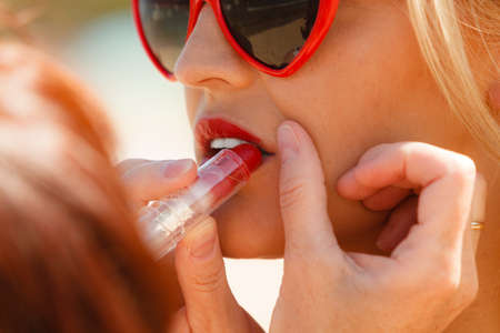 Pretty young blonde pretty girl at beach. Makeup arist making make up for woman care about look in summer. Summertime beauty concept.の写真素材