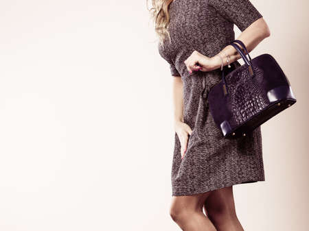 Fashion clothing people concept. Chic woman with black, leather handbag. Female wearing elegant dress.の写真素材