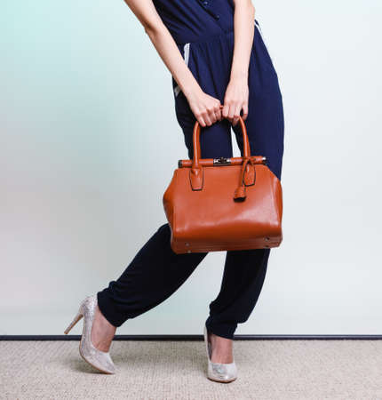 Elegant outfit. Stylish woman fashionable girl with brown leather handbag bag on green. Fashion and female beauty.の写真素材