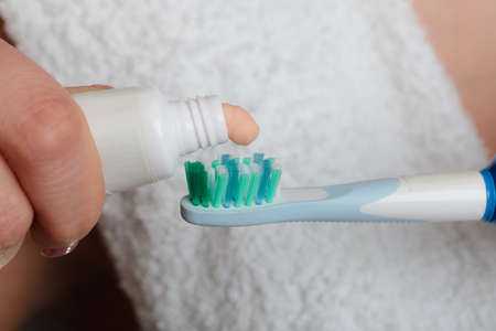 Dental health care. Closeup woman hands holding toothbrush and placing toothpaste on it.の写真素材