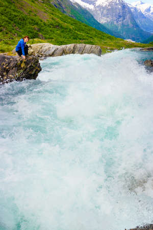 Travel, beauty in nature. Tourist woman looking at Videfossen (called Buldrefossen) waterfall in Norway Sogn og Fjordaneの写真素材