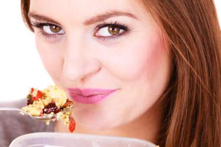 Woman eating oatmeal with nuts and dried fruits for breakfast. Girl holds plastic container take homemade lunch with healthy eating. Dieting nutrition conceptの写真素材