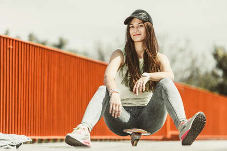 Summer sport and active lifestyle. Cool teenage girl skater riding skateboard on the street. Outdoor.の写真素材