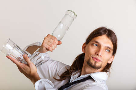 Drinking party liquor flair bartending concept. Bartender fills glass from bottle. Male tapster pours alcohol into glass.の写真素材