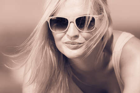 Young blonde pretty girl on beach. Woman wearing sunglasses have active time in summer. Summertime concept.の写真素材