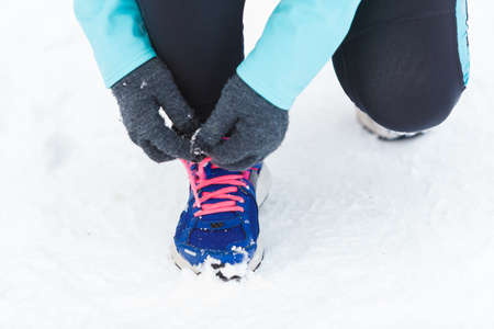 Footwear during winter time and workout outside. Shot of tying sholaces. Sporty trainers for wintry weather and doing exercises.の写真素材