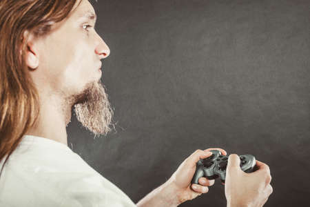 Lifestyle of young people. Student man spending time on playing games videogames console . Long haired guy focus on gaming.の写真素材