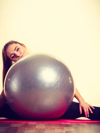 Fitness health activity sport gym concept. Fit girl lifting ball. Young sporty lady exercising with training gear.の写真素材