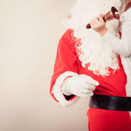 Xmas concept. Santa Claus with jingle bell. Christmas father has long white beard and red outfit.の写真素材