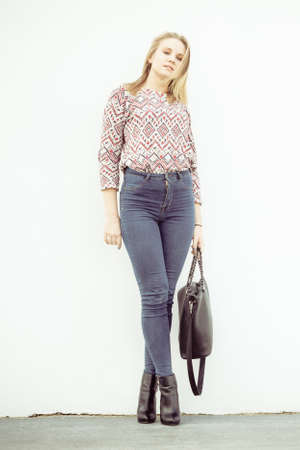 Urban style. Stylish fashionable beauty woman with black bag handbag. Blondie girl model posing...