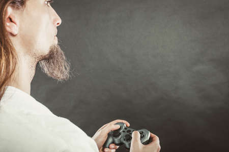Lifestyle of young people. Student man spending time on playing games videogames console playstation. Long haired guy focus on gaming.の写真素材