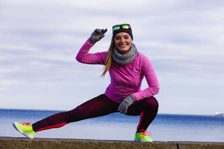 Woman athlete girl training wearing warm sporty clothes outside by seaside in cold weather. Sports...