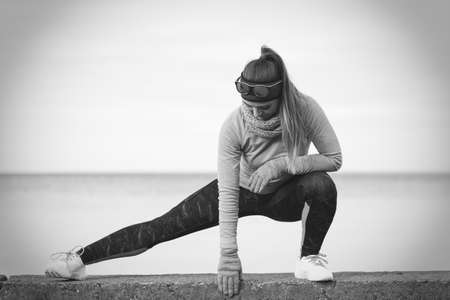 Woman athlete girl training wearing warm sporty clothes outside by seaside in cold weather. Sports and activities in winter or autumn time.の写真素材