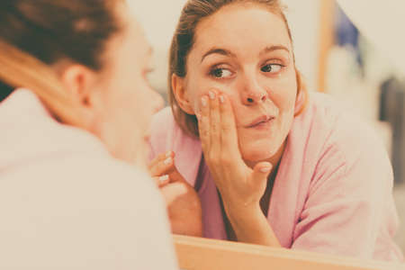 Woman cleaning peeling her face in bathroom, making facial massage with scrub. Girl taking care of skin condition. Hygiene. Skincare spa treatment.の写真素材