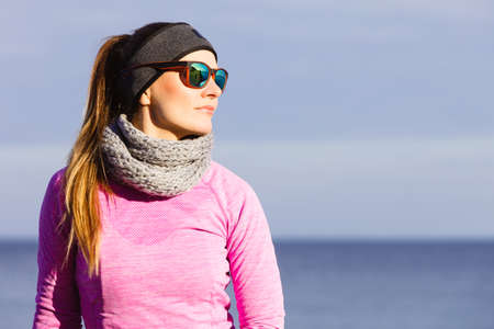 Woman resting relaxing after doing sports outdoors. Fitness girl female jogger wearing warm sporty...
