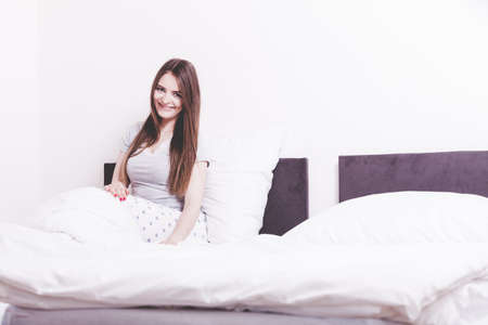 Mornings, chilling people concept. Attractive woman in the bed. Beautiful young lady has cosy pyjamas and long hair.の写真素材