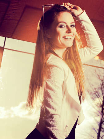Fashionable girl long haired portrait. Stylish woman enlightened by sunbeams. Attractive elegant female, positive smiling face expressionの写真素材