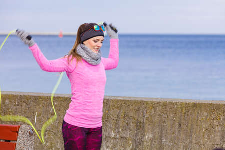 Woman athlete fit girl training outdoor with jumping skipping rope wearing warm sporty clothes in...