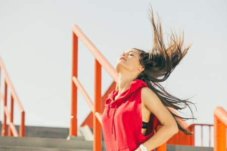 Young long haired girl on city stairs playing with her hair. Lifestyle funky in summer.