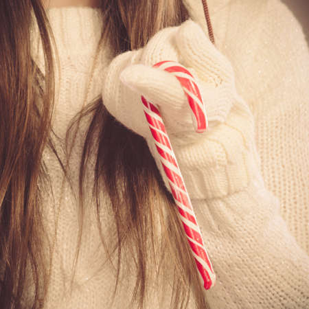Young woman holding xmas mug with candy cane. Girls hands in woolen white gloves. Christmas time concept.の写真素材