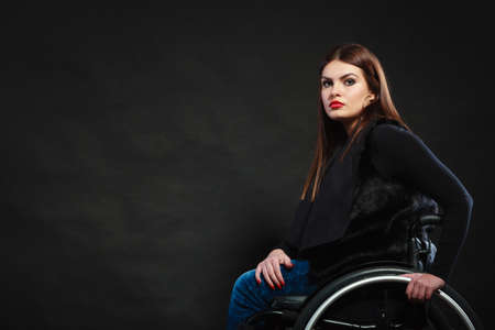 Disability sadness disease tragedy concept. Sad girl on wheelchair. Crippled young gorgeous lady casually dressed sitting on mobile chair.の写真素材