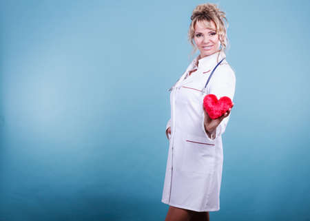 Help people concept. Medical idea of helping. Mature blonde happy doctor cardiologist with red heart...