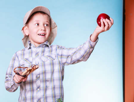 Nature and free time prankster little boy. Child have fun with  wooden sling shot and fruit hold apple.の写真素材