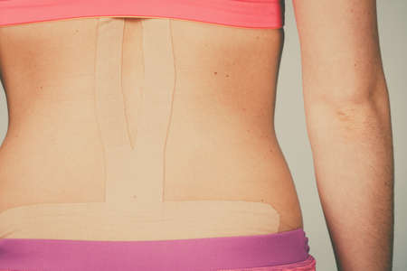 Woman with kinesiotaping application for back pain. Backache alternative kinesio tape therapy...