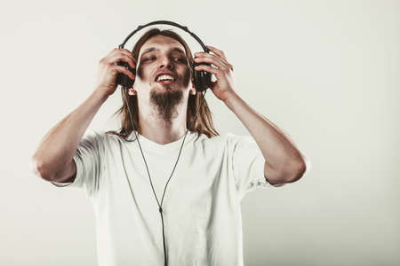 Music and sound. Young long haired happy man with headphones listening sounds. Communication.