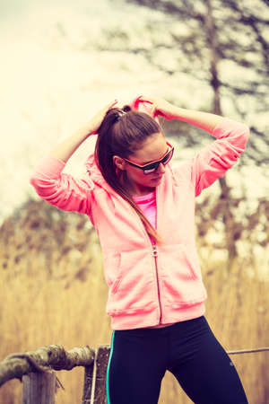 Sport and lifestyle concept. Young sports woman female jogger taking a break from running workout, relaxing on pier on sunny dayの写真素材