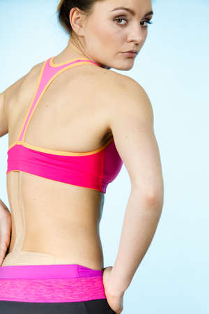 Woman with kinesiotaping application for back pain. Backache alternative kinesio tape therapy...