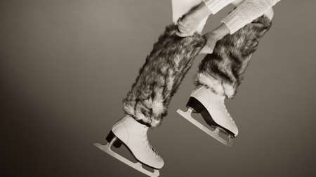 Woman legs wearing skates fur warm socks. Girl getting ready for ice skating. Winter sport activity. Studio shot b&w photoの写真素材