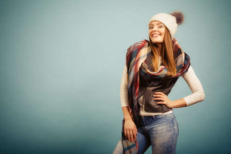 Autumnal outfit concept. Positive smiling young woman wearing warm autumn clothing woolen checked...